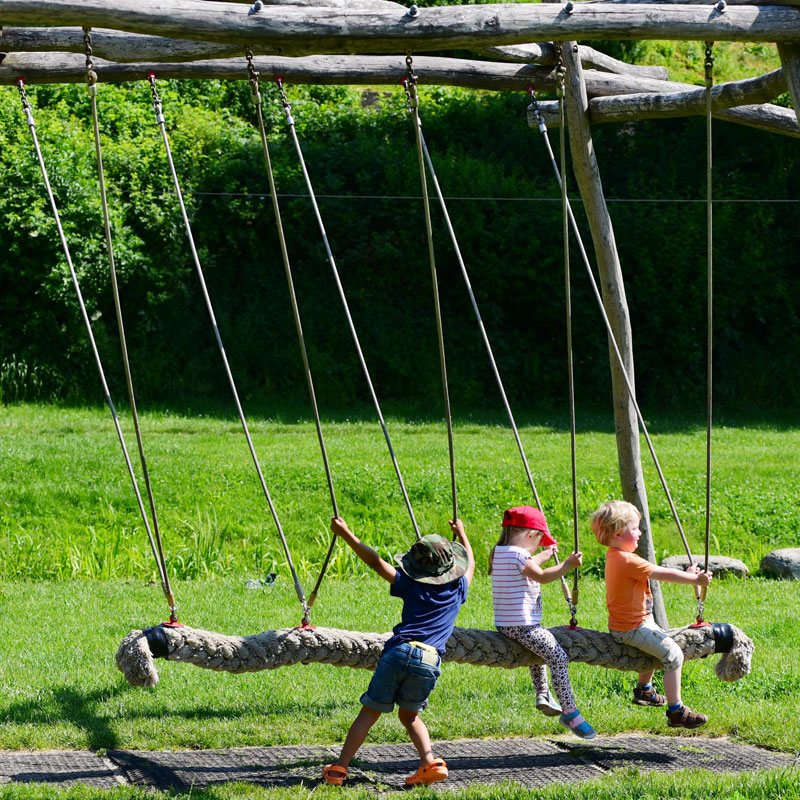 Drei Kinder auf einem Spielgerät beim Schaukeln