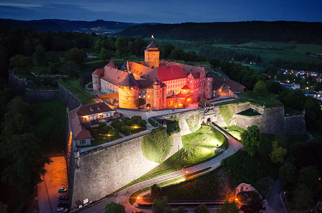 Luftaufnahme einer beleuchteten Burg bei Nacht