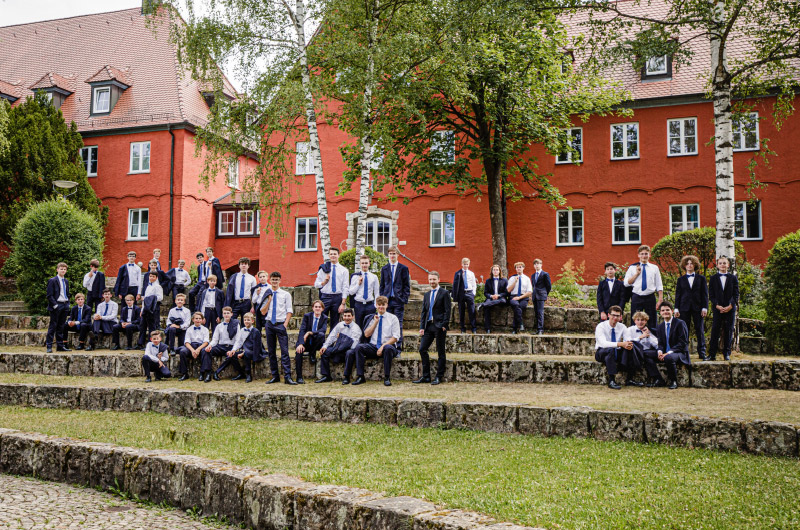 rund zwei Dutzend Kinder aus dem Knabenchor sitzen im Freien auf Stufen aus Naturstein