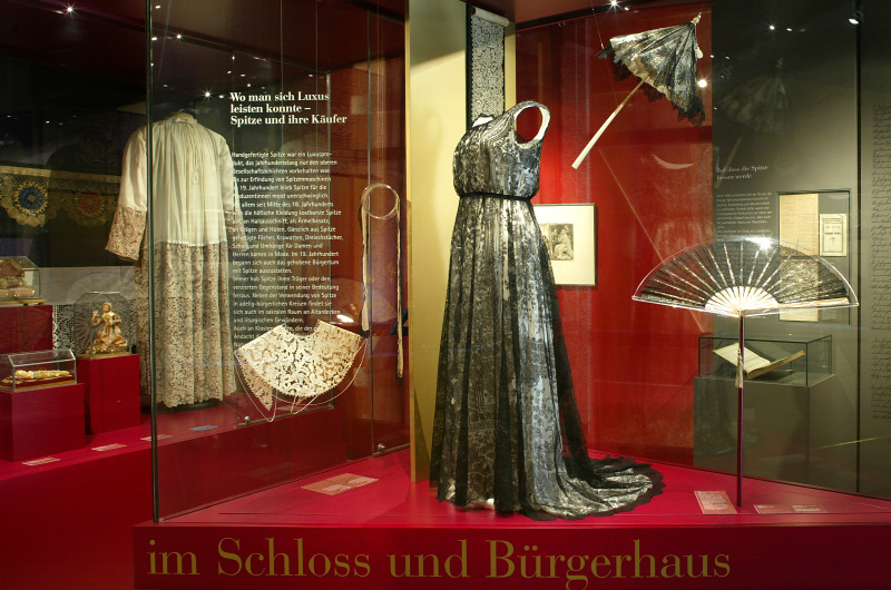 Ausstellung mehrerer aufwändig gefertigter Kleider mit Klöppelspitzen