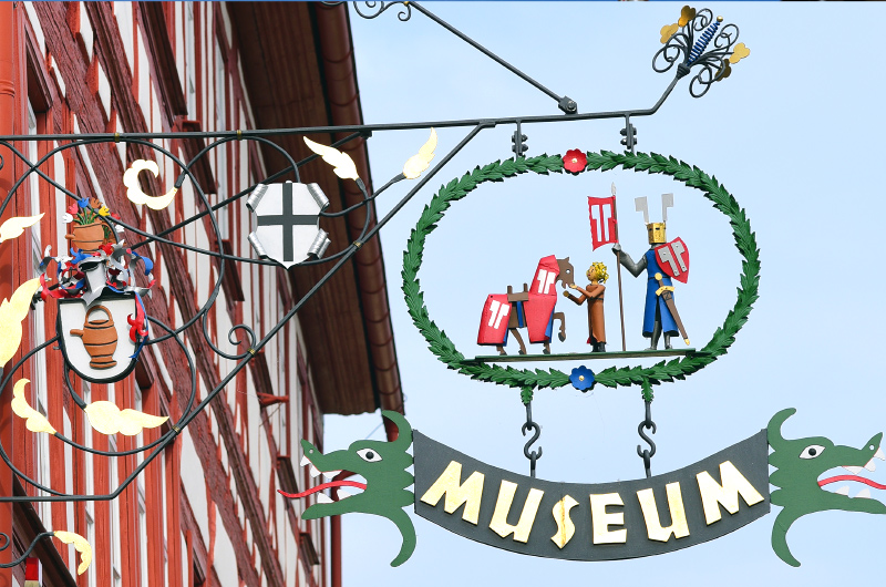 Auslegerarm mit bunten, kunstvoll gestaltetem Museumsschild