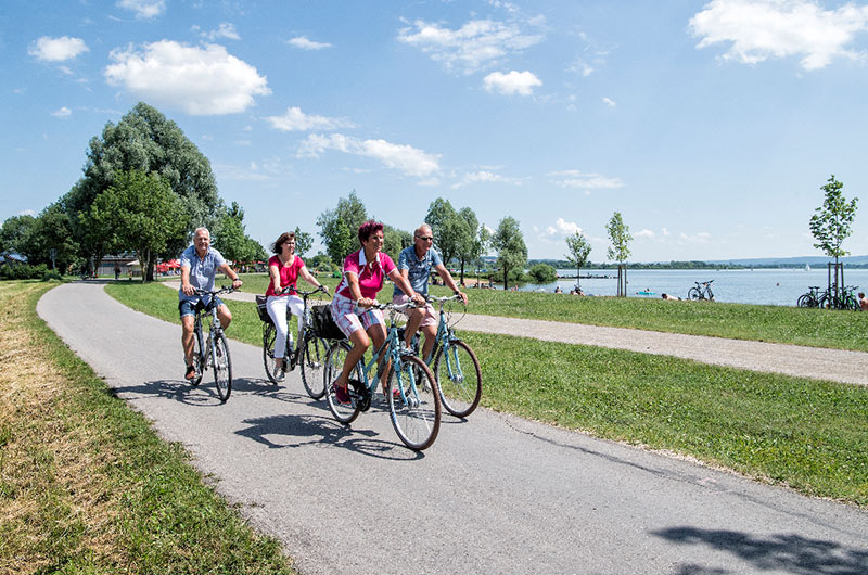 Fahrradfahrer auf einem Weg vor einem See