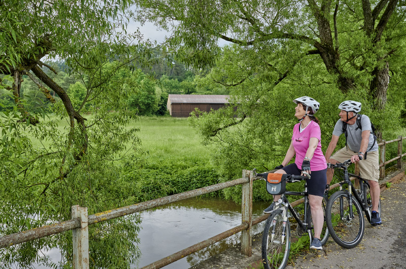 zwei Radfahrer machen Stopp auf einer Brücke im Grünen