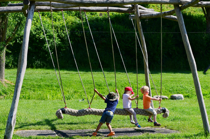 Drei Kinder auf einem Spielgerät beim Schaukeln