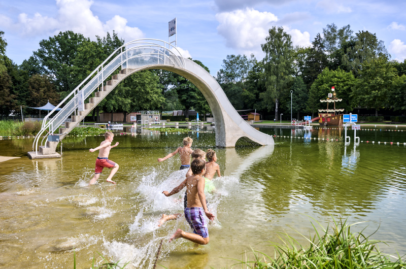 Mehrere Kinder toben im See des Waldstrandbads