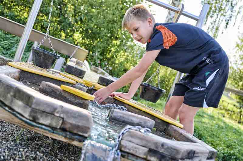 Ein Junge ändert den Wasserlauf an einem Wasserspielzeug